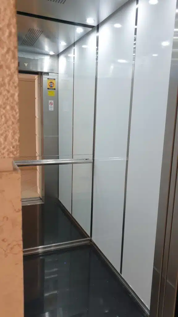 פנים מעלית מחודשת עם פנלים לבנים ומסגרות נירוסטה